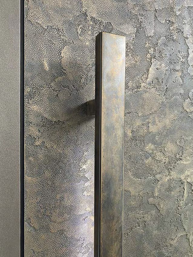 Złote drzwi pivot pokryte formowanym metalem ciekłym.